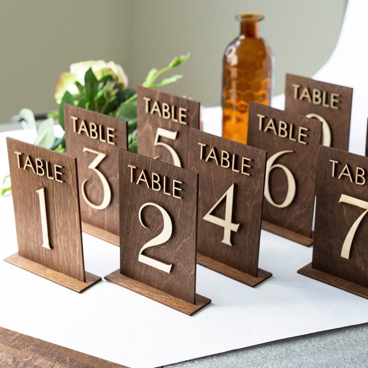 Rustic wooden table numbers 1-7 displayed on white tablecloth for wedding event