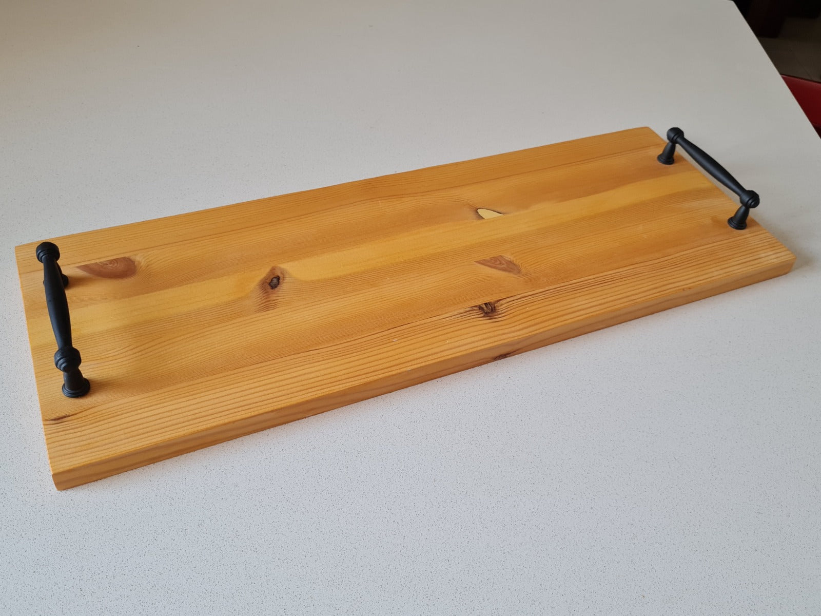 Natural pine wood serving board with black iron handles, empty