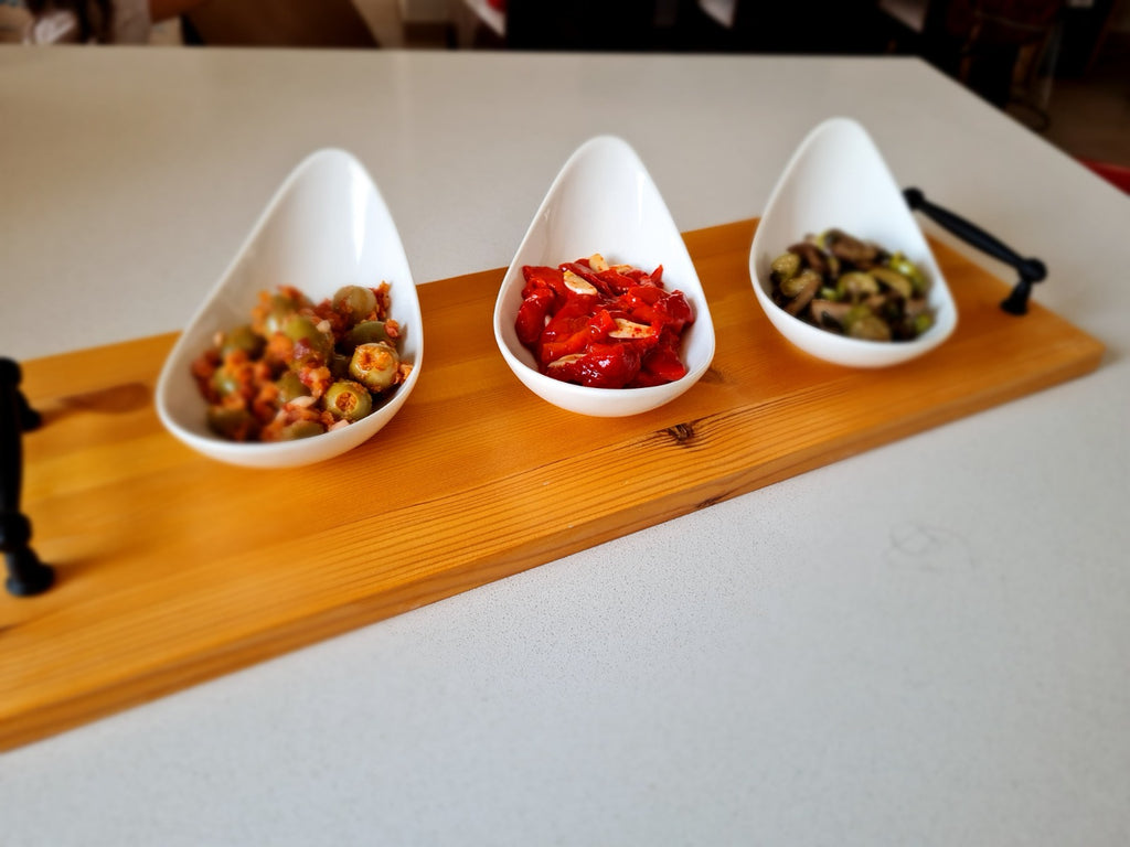 Wood serving board with 3 cone-shaped white bowls with appetizers