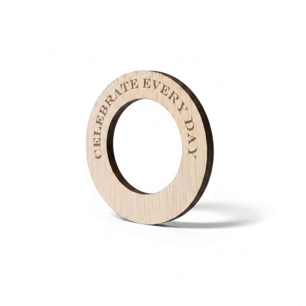 A light natural wood circular ring with the engraved text 'CELEBRATE EVERY DAY' on a clean white background.