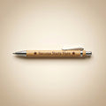A personalized bamboo pen with a silver clip and metal tip, featuring the engraved text 'Success Starts Here' with two stars, displayed on a warm beige background.