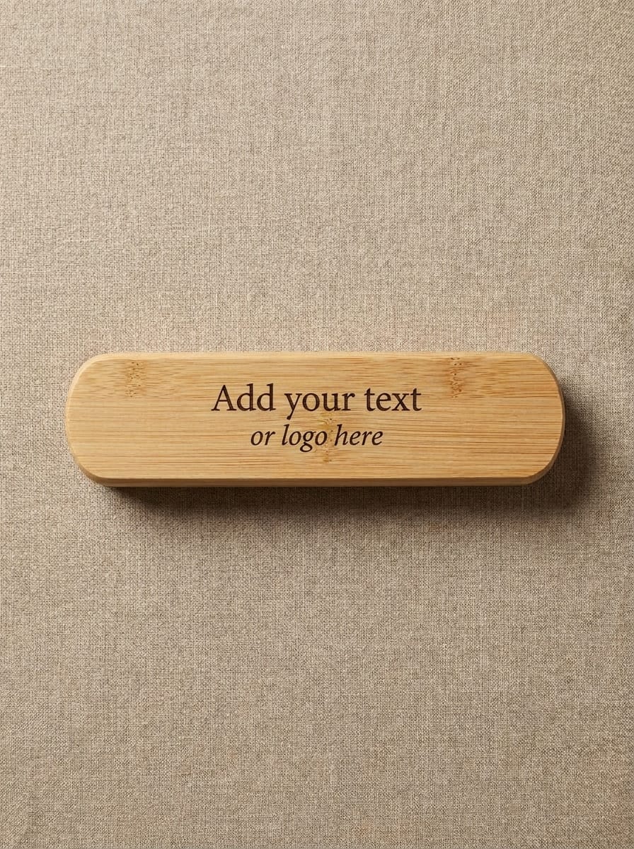 A light natural wood rectangular plaque with rounded ends, featuring the placeholder text 'Add your text or logo here' in dark brown, displayed on a textured beige linen background.
