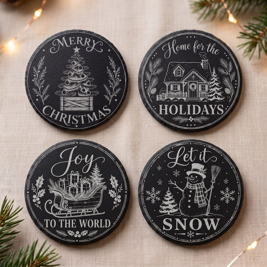 Four round black holiday coasters with white printed Christmas illustrations and phrases, arranged on a beige fabric surface with pine branches and warm string lights in the background.