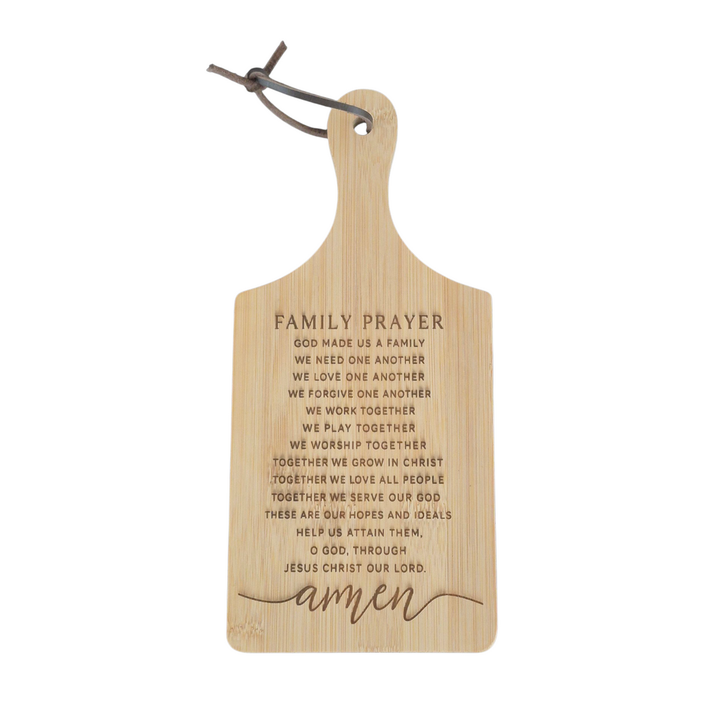 A rectangular wooden cutting board with a hanging loop and engraved family prayer text, shown on a plain white background.