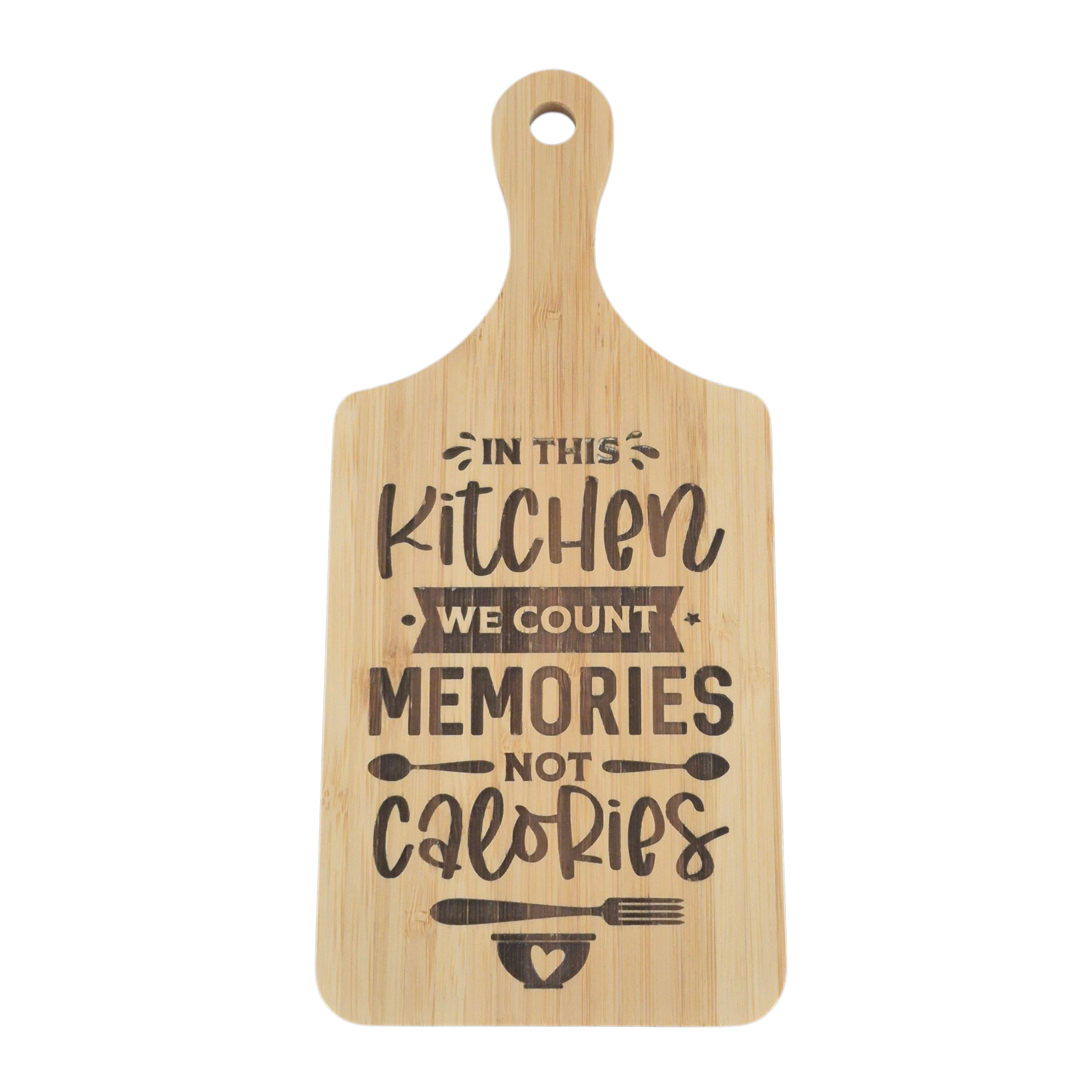 A rectangular wooden cutting board with a rounded handle and a hanging hole, featuring the engraved text 'IN THIS KITCHEN WE COUNT MEMORIES NOT CALORIES' with small kitchen utensil and heart illustrations, shown on a plain white background.