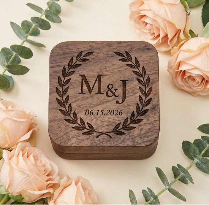 A square wooden keepsake box with rounded corners, engraved with a laurel wreath and the text 'M&J 06.15.